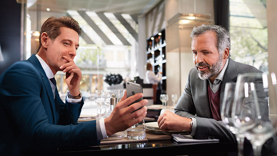 Gestionar tus lugares favoritos Dos hombres en un restaurante utilizan la función “Gestionar tus lugares favoritos” en el smartphone