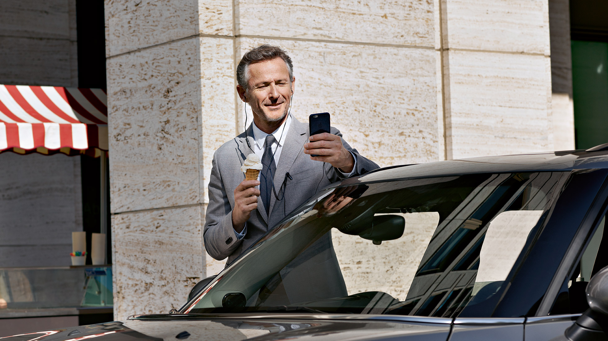 BMW Corporate Aftersales, control de finanzas BMW Corporate Aftersales: un hombre toma un helado y controla sus finanzas a través del smartphone