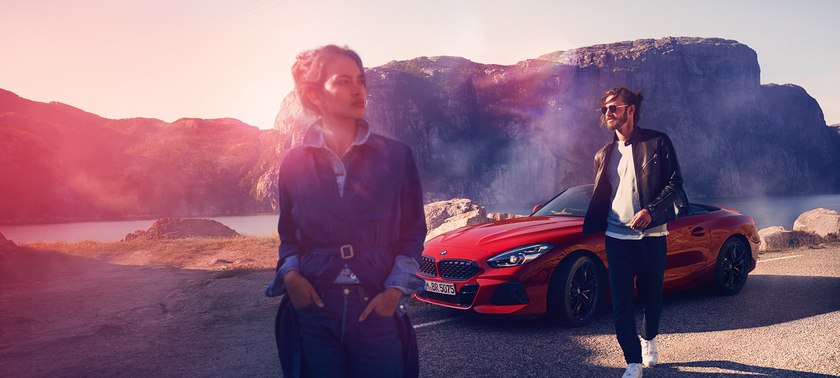 Vista de tres cuartos del frontal de un BMW delante de un paisaje de montaña con mujer y hombre BMW Financial Services Vista de tres cuartos del frontal delante de un paisaje de montaña con mujer y hombre