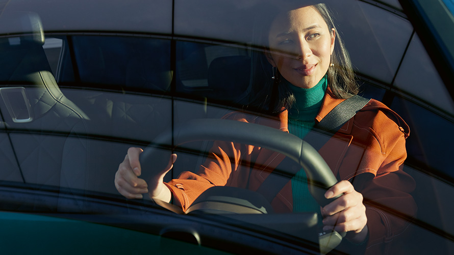 Mujer al volante de un BMW Mujer con chaqueta naranja al volante de un BMW