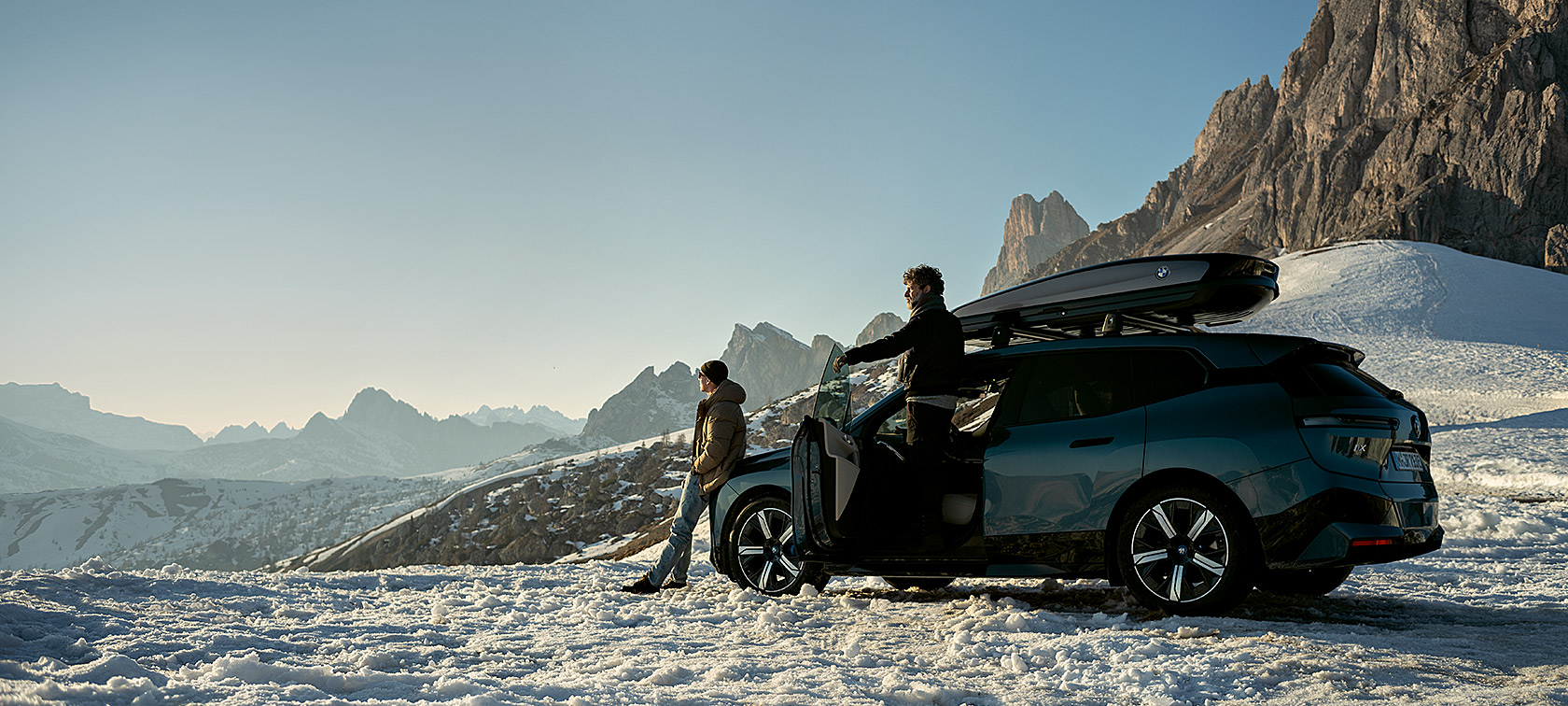 Accesorios Originales BMW y BMW Service para otoño e invierno Hombres con BMW iX en un paisaje nevado