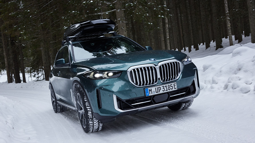 Ruedas completas de invierno BMW en un BMW X5 (G05 LCI) en una carretera cubierta de nieve en el bosque ' Ruedas completas de invierno BMW en un BMW X5 (G05 LCI) en una carretera cubierta de nieve en el bosque