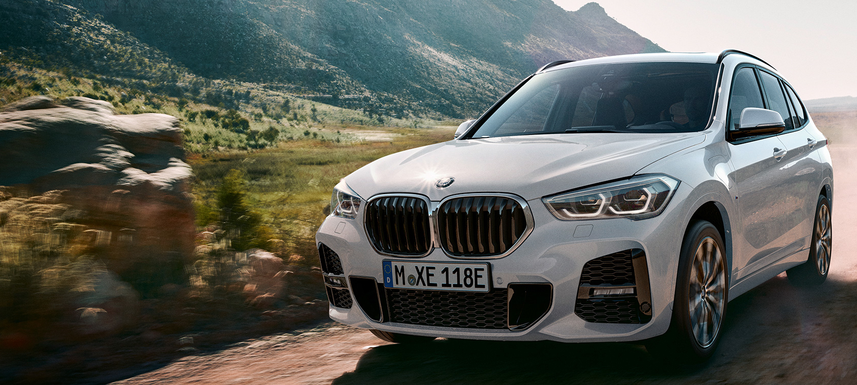 BMW X1 SUV F48, vista de tres cuartos de la zaga. Vista de tres cuartos de la zaga del todoterreno de BMW delante de un paisaje montañoso F48.