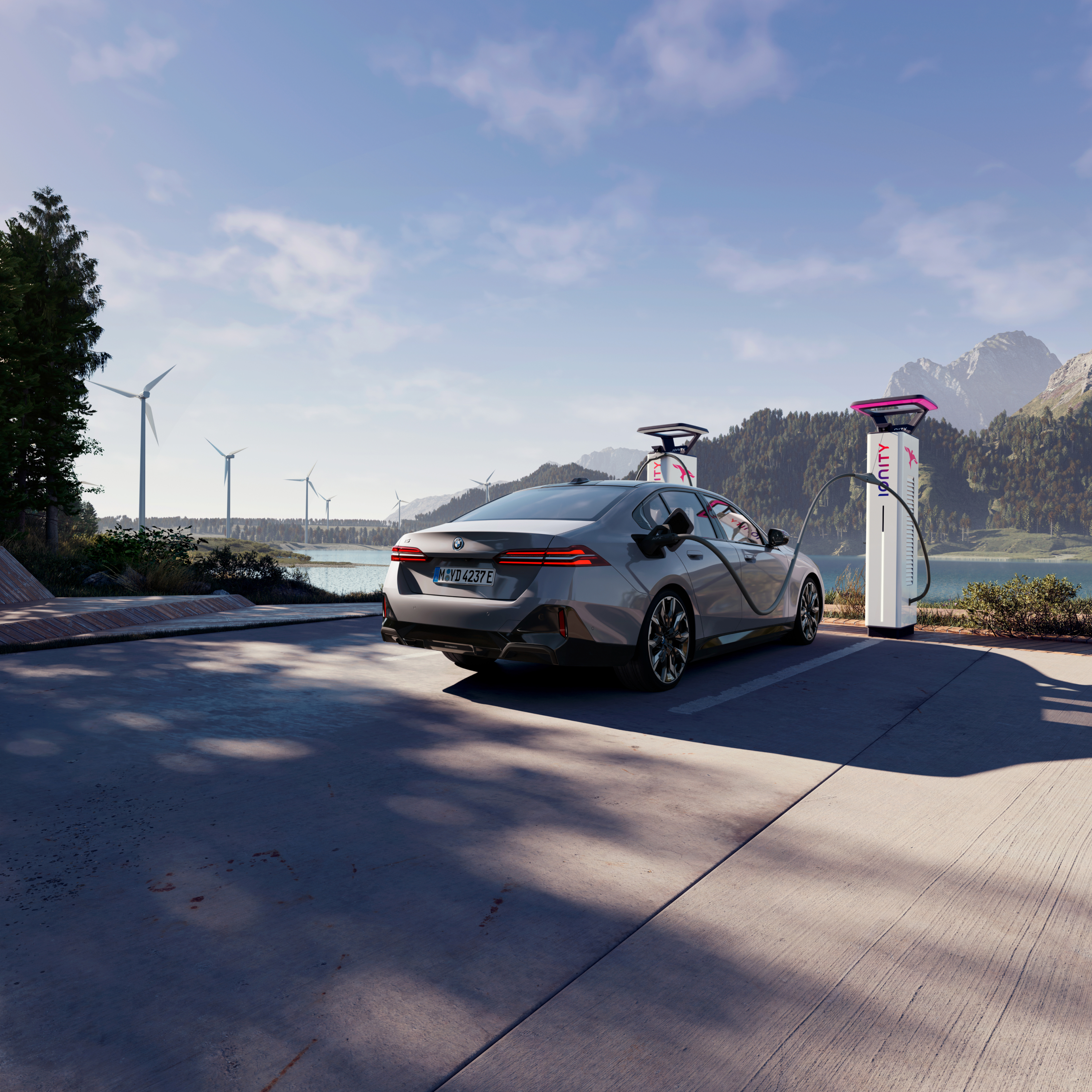 Un BMW cargándose en un poste de carga con vistas al agua, las montañas y carga en una estación de carga con vistas al agua, las montañas y las turbinas eólicas